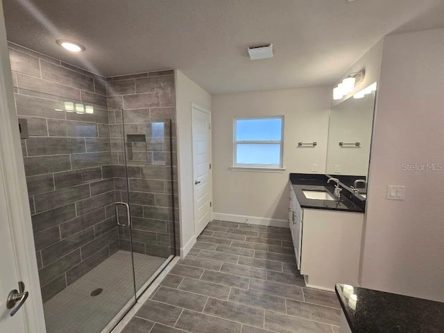 bathroom featuring a stall shower, vanity, and baseboards