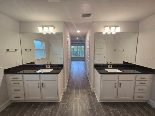 bathroom with two vanities, wood finish floors, visible vents, and a sink