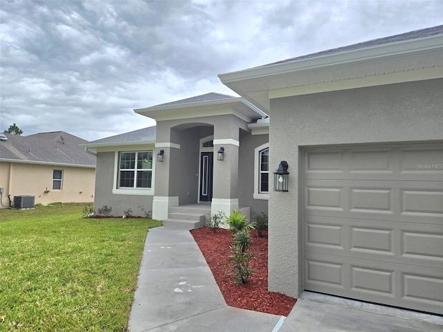 entrance to property featuring stucco siding, a shingled roof, a lawn, an attached garage, and cooling unit