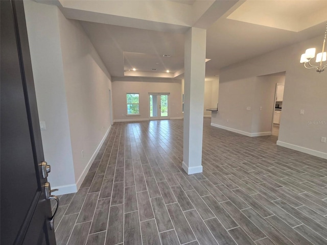 interior space featuring baseboards, a chandelier, a tray ceiling, and wood finish floors