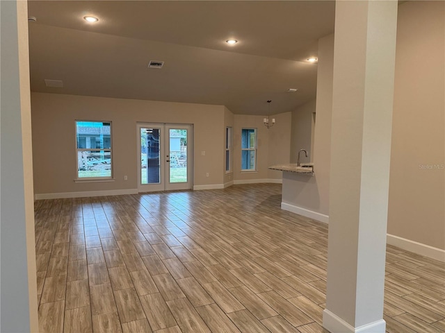 unfurnished living room with french doors and a chandelier