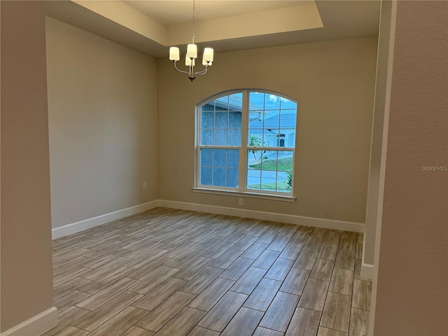 empty room featuring a chandelier and a raised ceiling