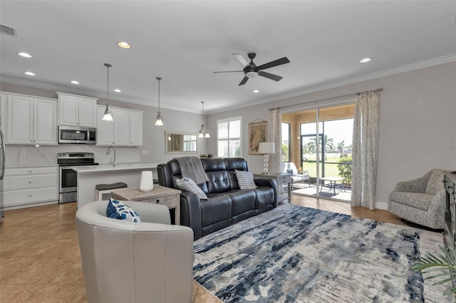 living room featuring crown molding, sink, light tile patterned flooring, and ceiling fan with notable chandelier