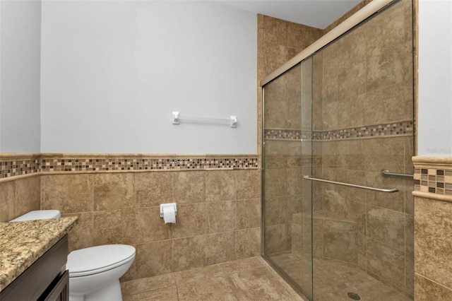 bathroom featuring an enclosed shower, vanity, toilet, and tile walls