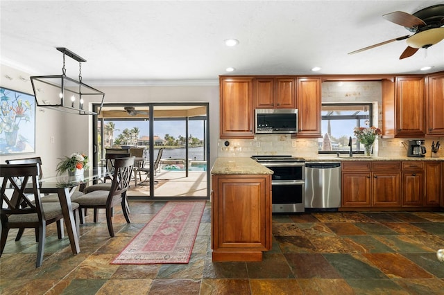 kitchen with pendant lighting, sink, decorative backsplash, light stone countertops, and appliances with stainless steel finishes