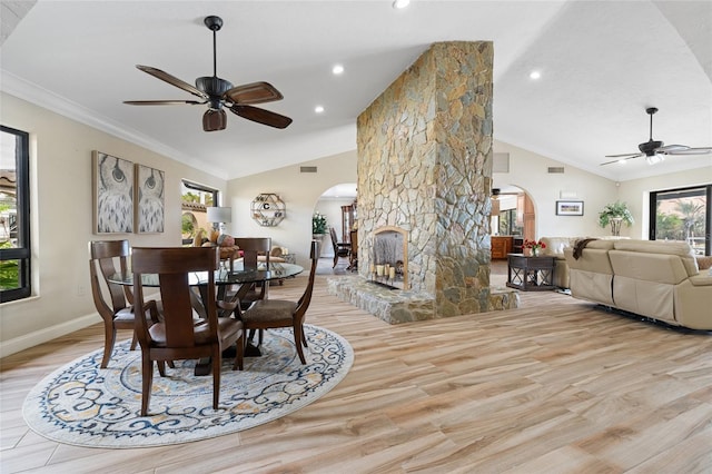 dining space with a fireplace, light hardwood / wood-style floors, vaulted ceiling, and ceiling fan