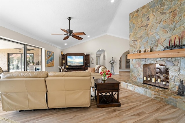 living room with ceiling fan, crown molding, hardwood / wood-style flooring, a fireplace, and lofted ceiling