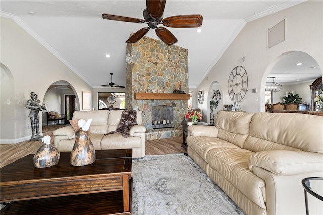 living room featuring hardwood / wood-style flooring, ornamental molding, a fireplace, and vaulted ceiling