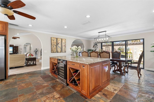 kitchen featuring pendant lighting, light stone counters, beverage cooler, and ornamental molding