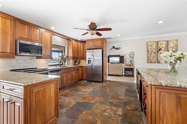 kitchen with ceiling fan, ornamental molding, appliances with stainless steel finishes, and tasteful backsplash