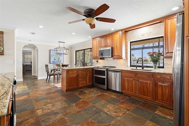 kitchen featuring sink, stainless steel appliances, kitchen peninsula, pendant lighting, and decorative backsplash