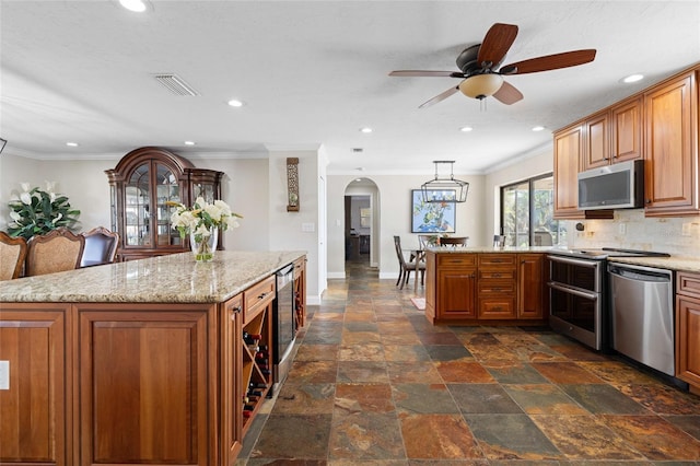 kitchen featuring appliances with stainless steel finishes, backsplash, a kitchen island, and pendant lighting