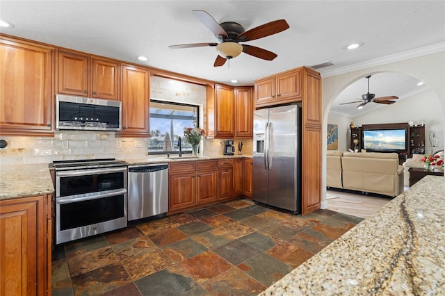 kitchen with sink, stainless steel appliances, tasteful backsplash, light stone counters, and crown molding