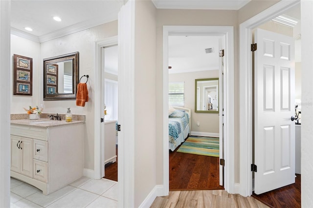 bathroom with hardwood / wood-style flooring, vanity, and crown molding