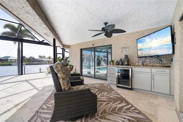 interior space with ceiling fan, a lanai, wine cooler, area for grilling, and a water view