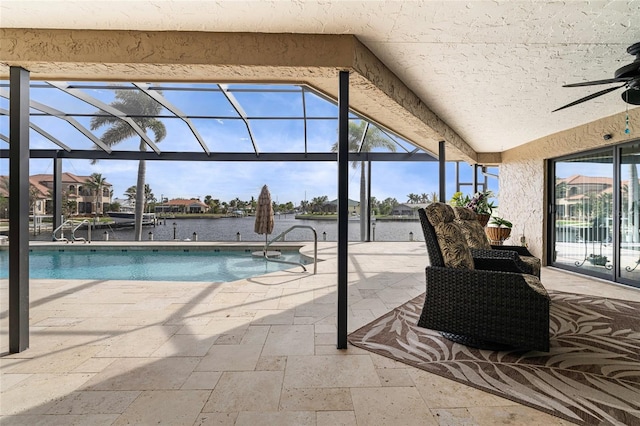 view of swimming pool featuring a lanai, ceiling fan, a water view, and a patio