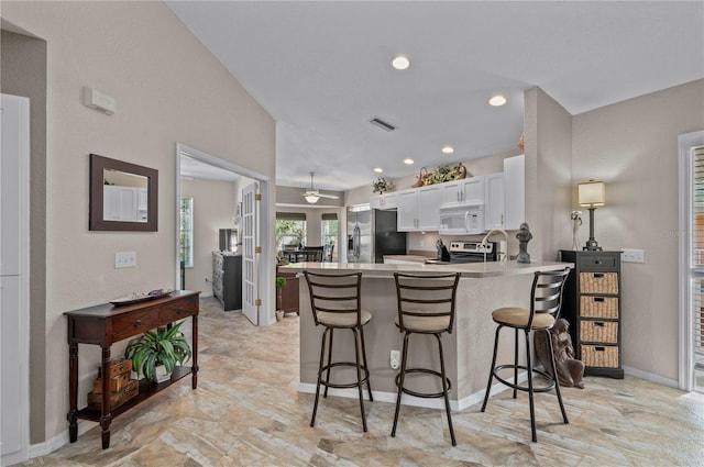 kitchen featuring white cabinetry, a breakfast bar, kitchen peninsula, and appliances with stainless steel finishes