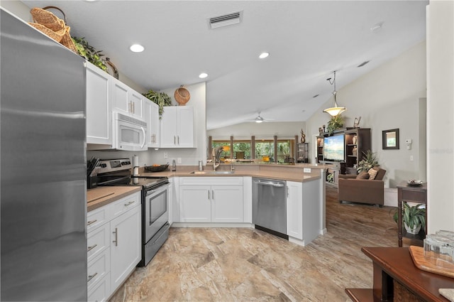 kitchen featuring sink, white cabinetry, vaulted ceiling, kitchen peninsula, and appliances with stainless steel finishes