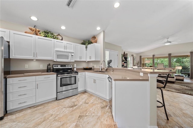 kitchen with lofted ceiling, a breakfast bar area, white cabinetry, and appliances with stainless steel finishes