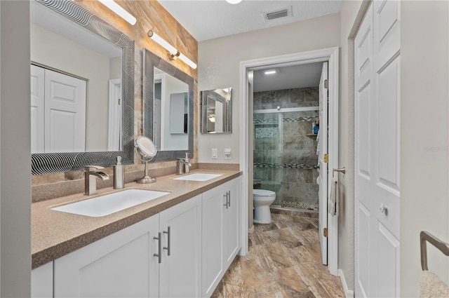 bathroom with toilet, vanity, and a shower with shower door