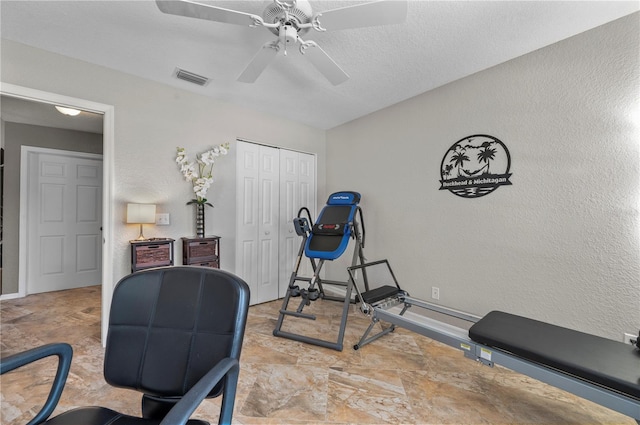 exercise room featuring ceiling fan and a textured ceiling