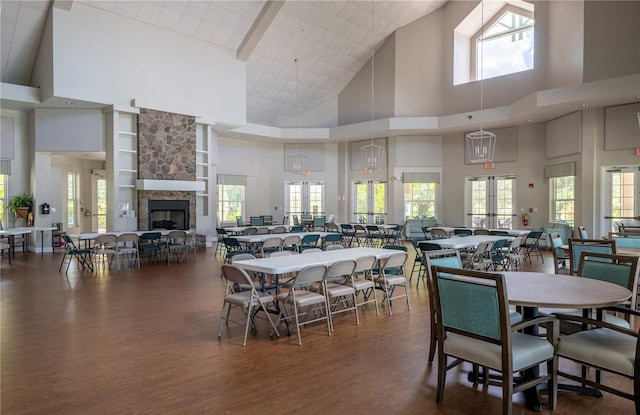 dining room featuring a stone fireplace, french doors, dark hardwood / wood-style floors, a high ceiling, and built in shelves