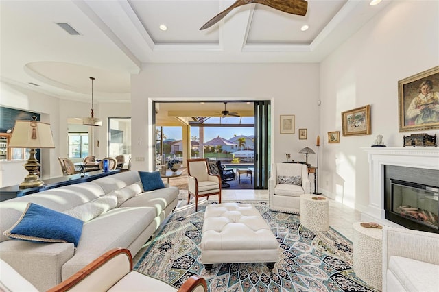 living room featuring a tray ceiling, ceiling fan, tile patterned flooring, and a healthy amount of sunlight