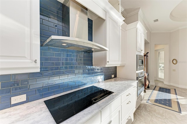 kitchen featuring backsplash, white cabinetry, wall chimney range hood, and appliances with stainless steel finishes