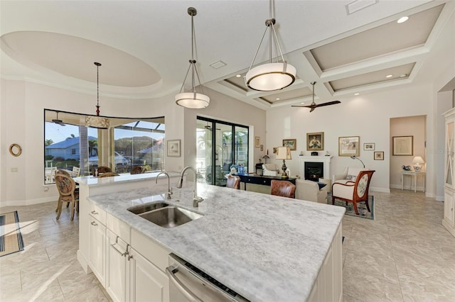 kitchen featuring coffered ceiling, a kitchen island with sink, sink, decorative light fixtures, and white cabinetry