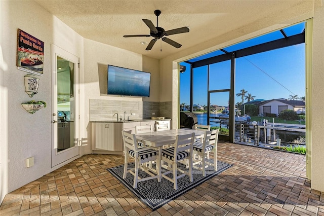 sunroom featuring ceiling fan and sink