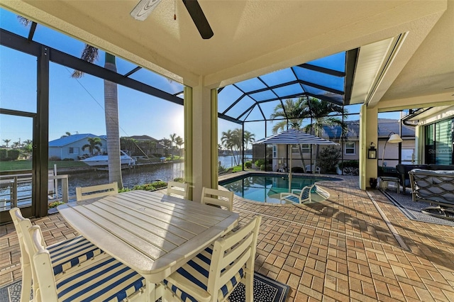 view of pool featuring ceiling fan, a patio area, a water view, and glass enclosure