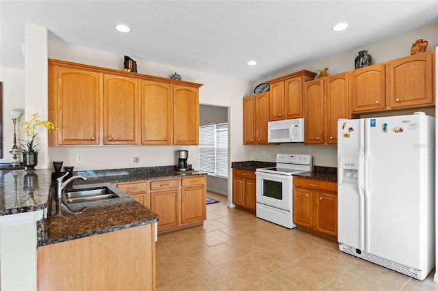 kitchen featuring kitchen peninsula, white appliances, dark stone counters, and sink