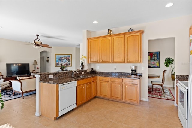 kitchen with dark stone countertops, white appliances, kitchen peninsula, and light tile patterned floors