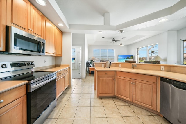 kitchen featuring ceiling fan, sink, stainless steel appliances, a raised ceiling, and light tile patterned flooring