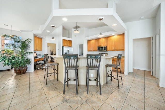 kitchen with a breakfast bar, light tile patterned floors, hanging light fixtures, and appliances with stainless steel finishes