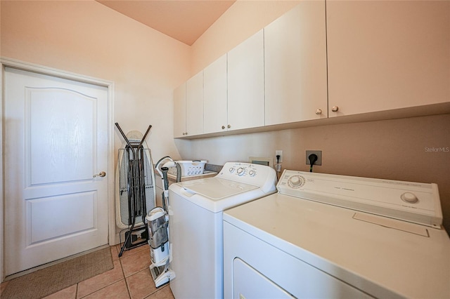 laundry area featuring washer and clothes dryer, light tile patterned flooring, and cabinets