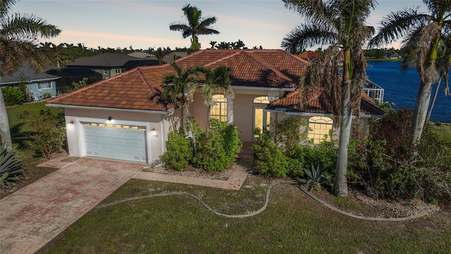 mediterranean / spanish-style house with a garage, a water view, and a yard