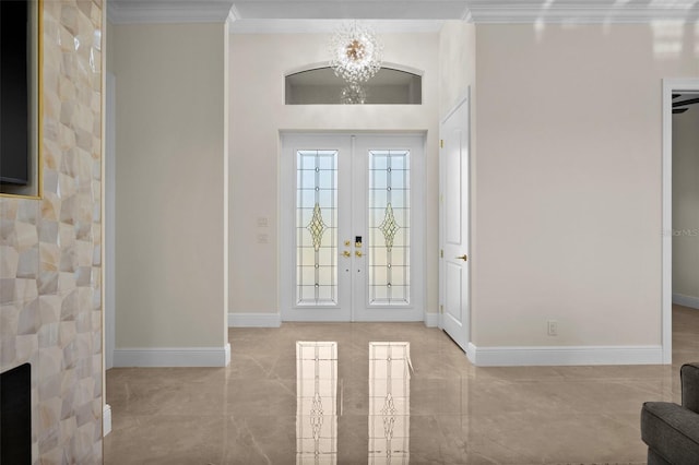 entryway with a large fireplace, crown molding, french doors, and an inviting chandelier