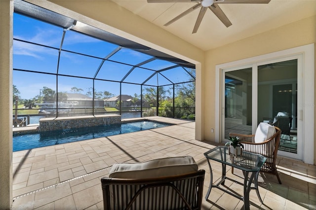 view of pool with glass enclosure, ceiling fan, a patio area, and a water view