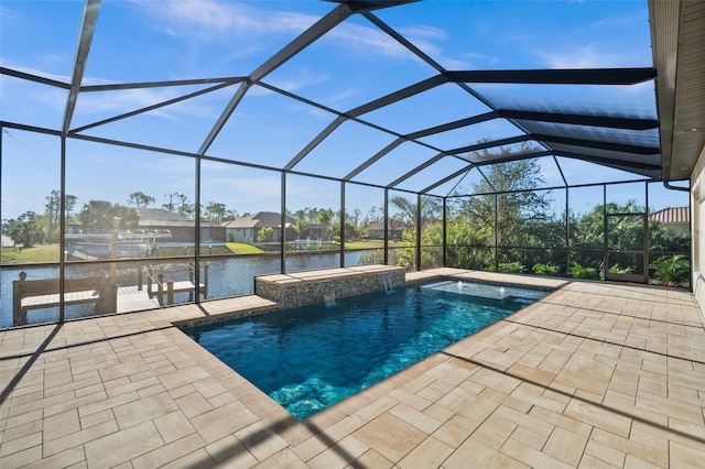 view of pool with glass enclosure, a patio area, and a water view