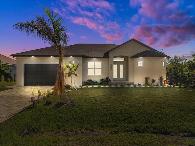 view of front of property featuring french doors, a yard, and a garage