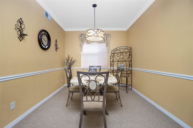 carpeted dining room with ornamental molding