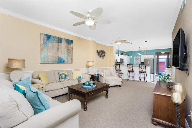 carpeted living room with ceiling fan and crown molding