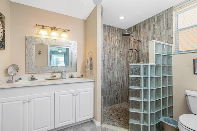 bathroom featuring tiled shower, vanity, toilet, and a wealth of natural light