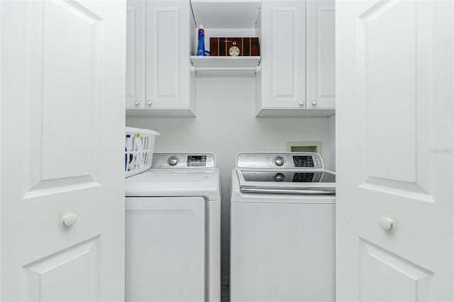 clothes washing area with washer and clothes dryer and cabinets