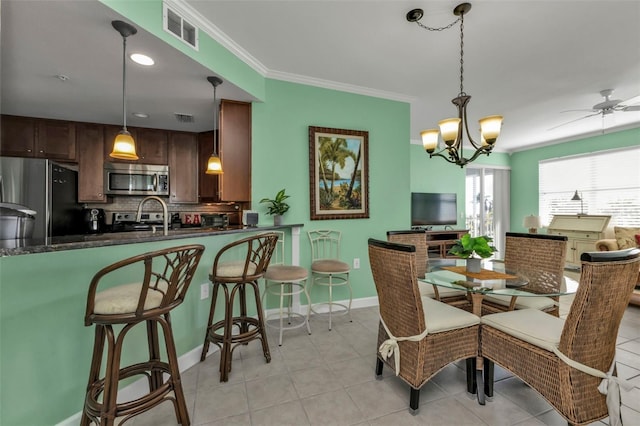 dining room with ceiling fan with notable chandelier, ornamental molding, sink, and light tile patterned floors