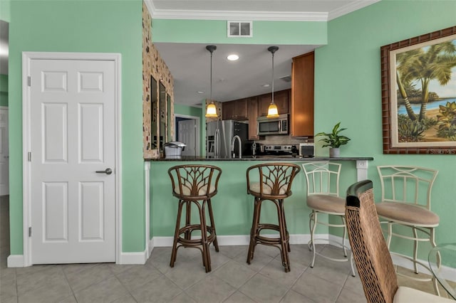 kitchen with pendant lighting, a kitchen breakfast bar, ornamental molding, kitchen peninsula, and stainless steel appliances