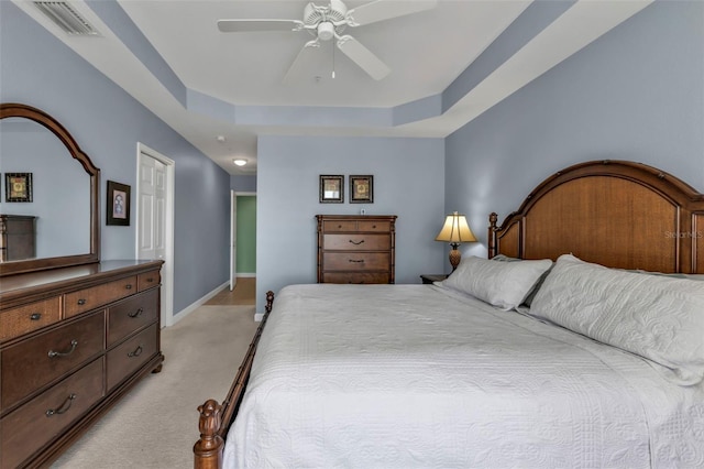 carpeted bedroom featuring a raised ceiling and ceiling fan