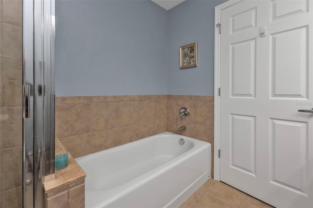 bathroom featuring tile patterned floors, a bathtub, and tile walls