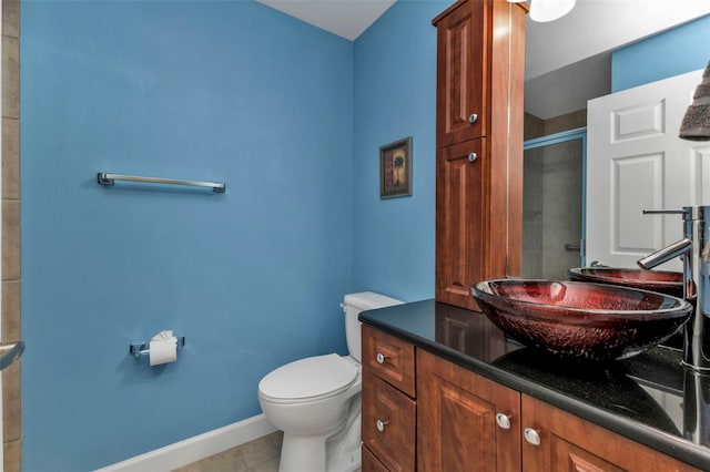 bathroom featuring tile patterned floors, vanity, toilet, and a shower with shower door